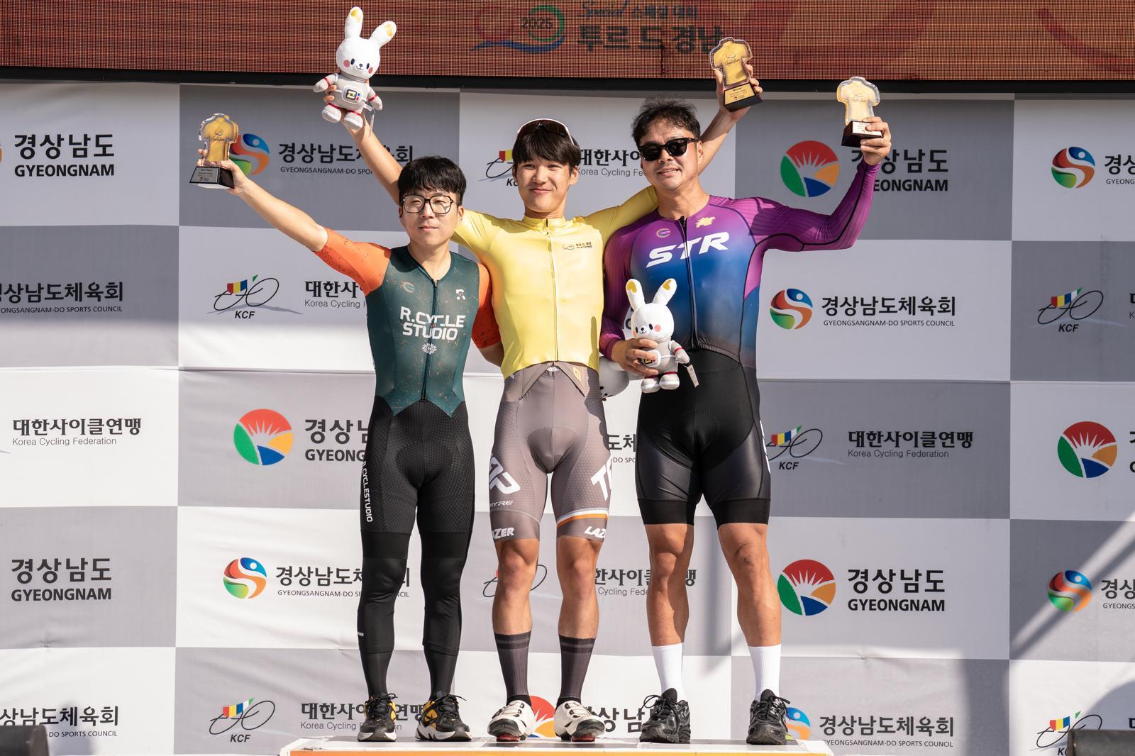 류금찬 씨(가운데)가 9일 끝난 ‘투르 드 경남 2025 스페셜 대회’에서 개인 종합 1위를 차지한 뒤 시상대에 올라 정우람 씨(2위·왼쪽), 박한흙 씨(3위)와 함께 기념 촬영을 하고 있다. 경남도 제공