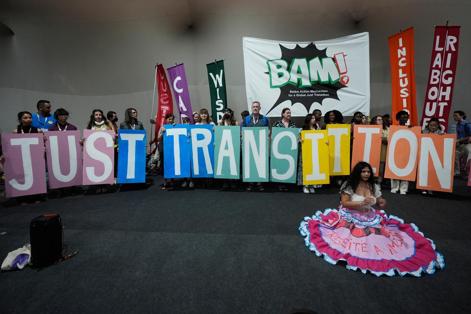 11일(현지 시간) 브라질 벨렝에서 열린 제30차 유엔기후변화협약 당사국 총회(COP30) 행사장에서 환경단체 관계자 등이 화석연료 탈피를 의미하는 ‘정의로운 전환(just transition)’이란 문구가 적힌 팻말을 보이고 있다. 벨렝=AP 뉴시스