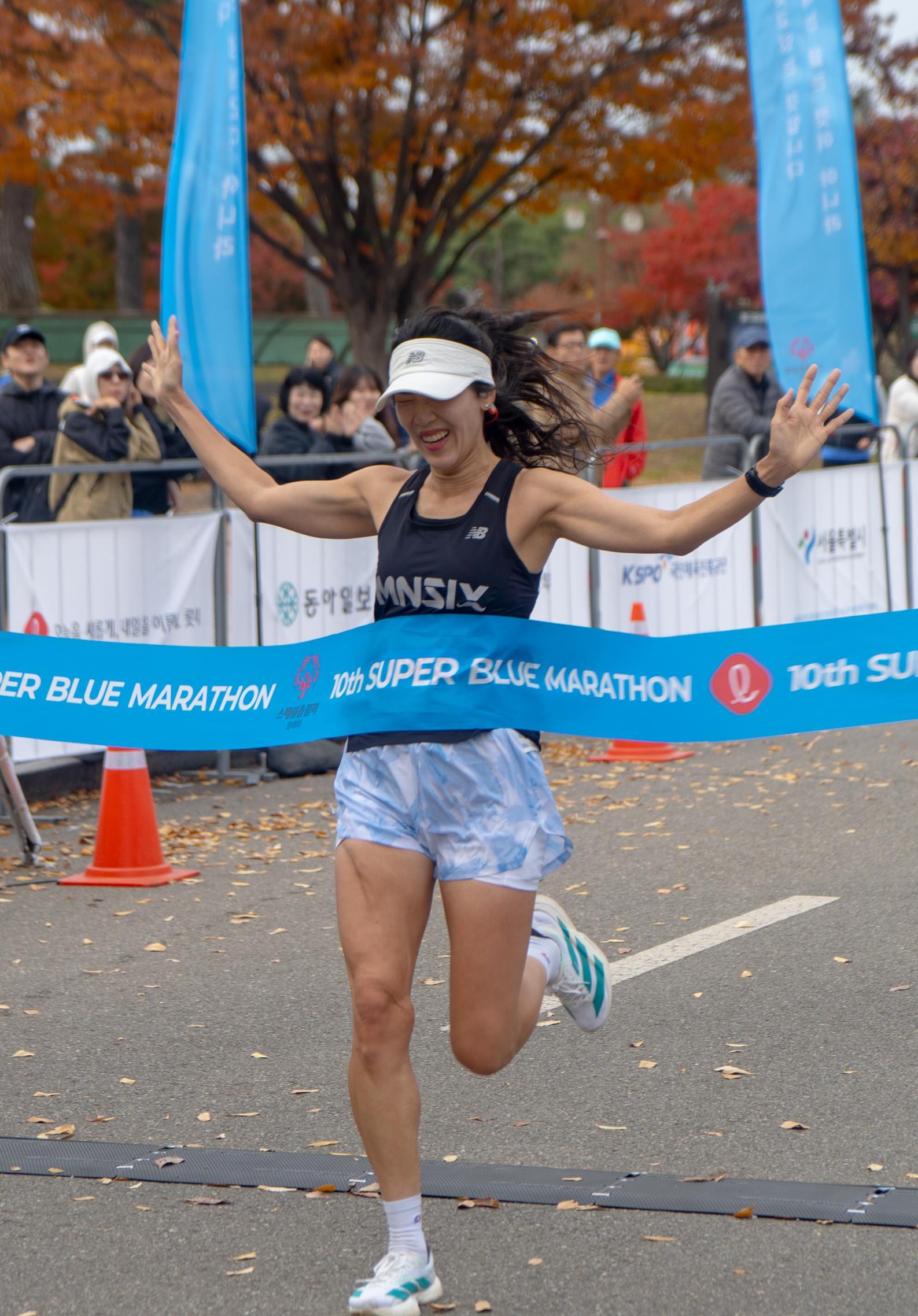 ‘제10회 슈퍼블루마라톤’에 참가한 여성 참가자가 골인을 하며 환호하고 있다.
