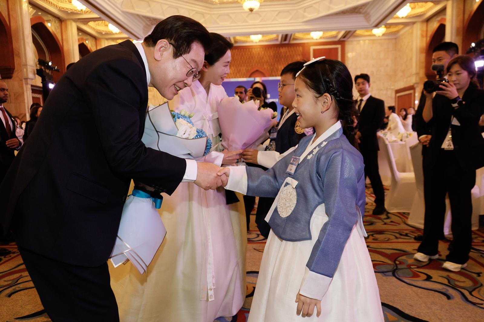 이재명 대통령과 김혜경 여사가 17일 아랍에미리트 아부다비에서 열린 동포만찬간담회에 참석해 화동에게 꽃다발을 받고 있다. 2025.11.17 대통령실사진기자단