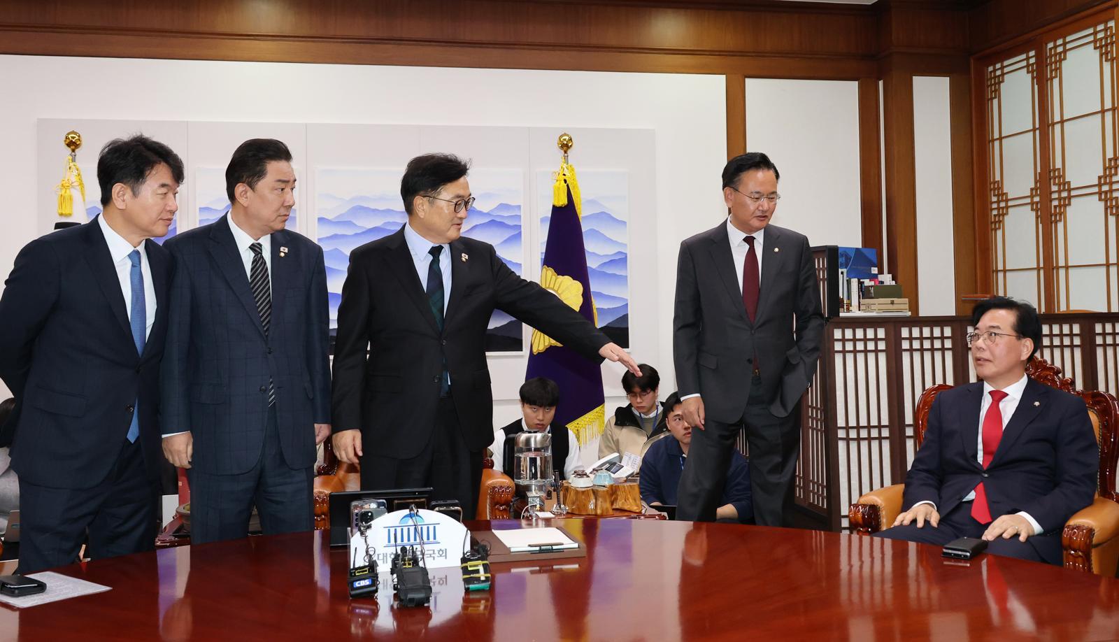 우원식 국회의장(가운데)이 27일 서울 여의도 국회 의장실에서 열린 여야원내대표 회동에서 송언석 국민의힘 원내대표(오른쪽)가 기념촬영을 거부하고 자리에 앉아버리자 자리에 일어나라고 요청하고 있다. 왼쪽부터 문진석 더불어민주당 원내수석부대표, 김병기 원내대표, 우 의장, 유상범 국민의힘 원내수석부대표, 송 원내대표. 2025.11.27/사진공동취재단