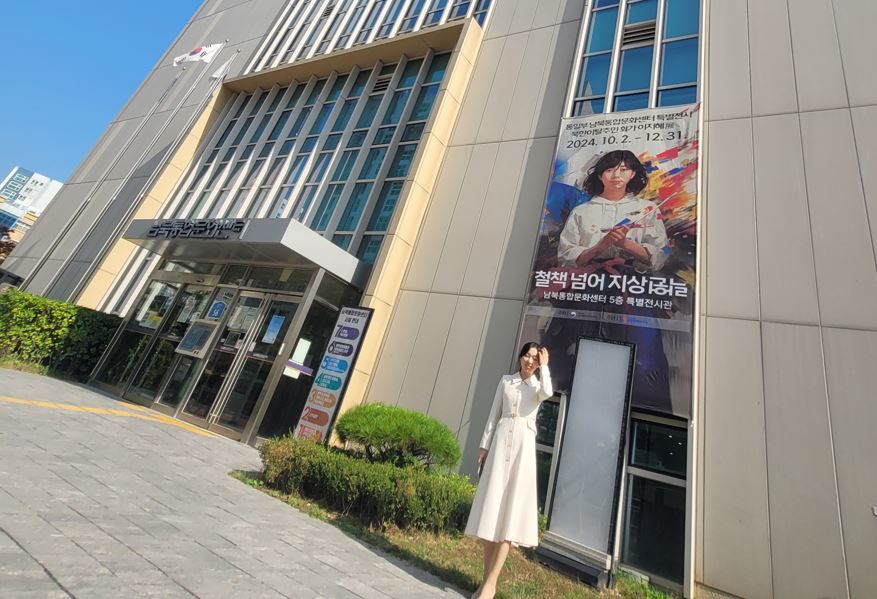 지난해 10월 남북통합문화센터 그림 전시회장 앞에서 이지혜 씨가 전시회 포스터 앞에 서 있다.