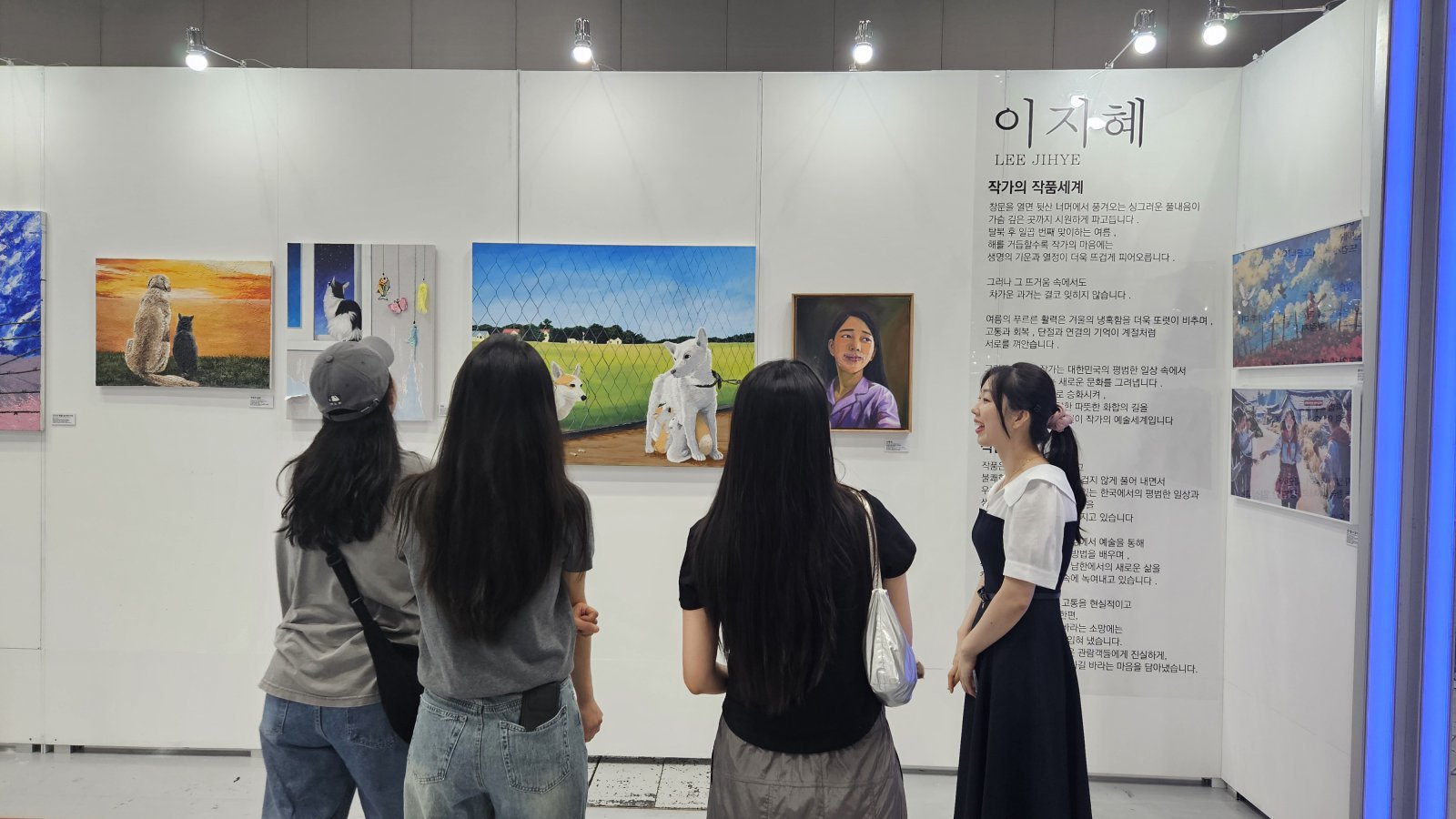 올해 7월 ‘북한이탈주민의 날’을 맞아 서울 강남구 코엑스에서 열린 ‘탈북 청년 작가 5인 전시회’에서 이지혜 씨(오른쪽)가 관람객들에게 자신의 그림을 설명하고 있다.
