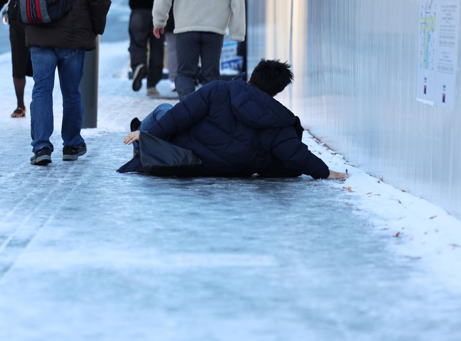 폭설 후 한파로 도로 곳곳이 얼어붙은 5일 오전 서울 광화문역 일대에서 한 시민이 빙판길에 미끄러져 넘어지고 있다.  2025.12.5 뉴스1