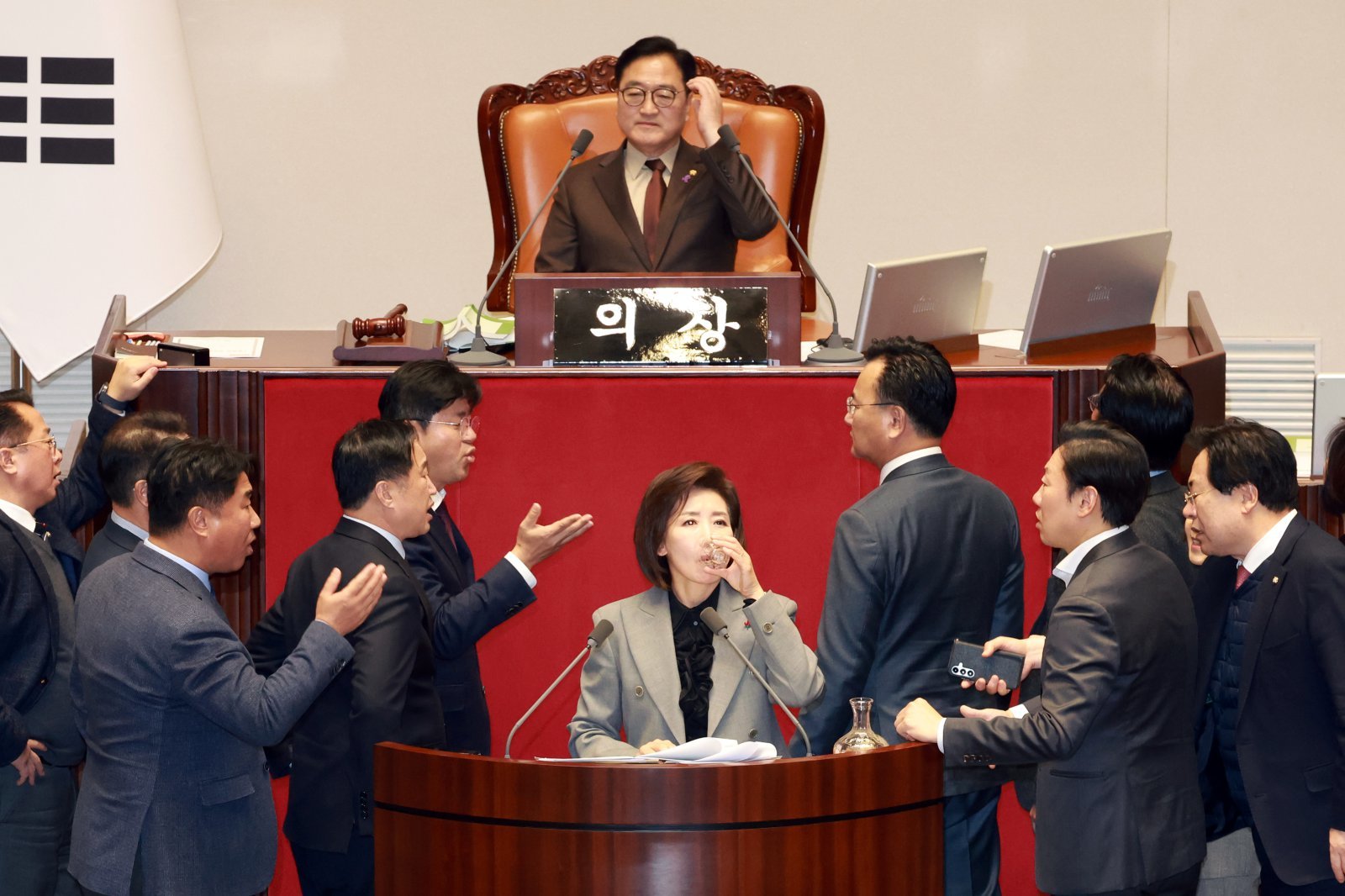 나경원 국민의힘 의원이 9일 서울 여의도 국회에서 열린 제429회국회(정기회) 제16차 본회의에서 가맹사업거래의 공정화에 관한 법률 일부개정법률안에 대한 필리버스터를 하던 중 의제와는 관련없는 발언을 이어가며 물을 마시고 있다. 여야 의원들이 나와 언쟁을 벌이고 있다. 2025.12.09 뉴시스