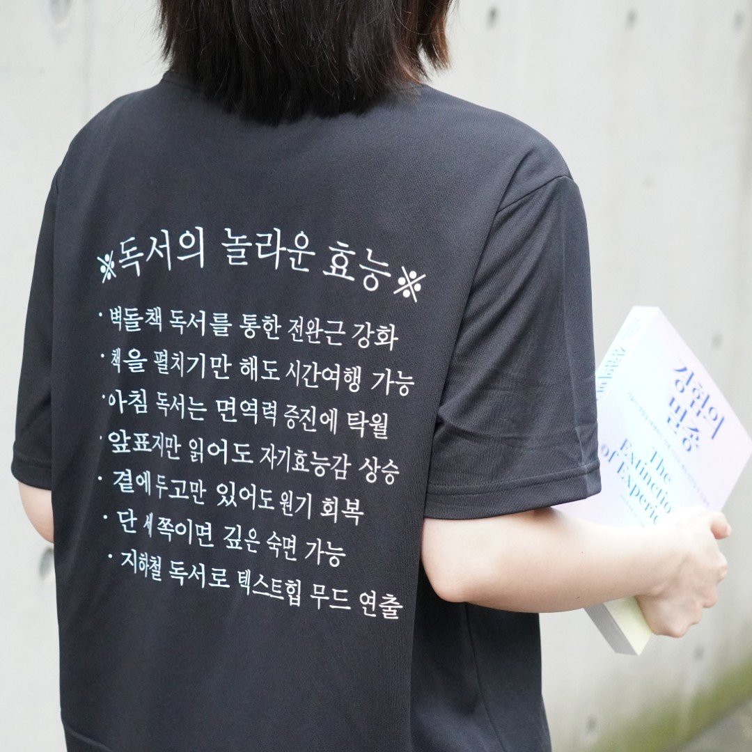 ‘독서의 놀라운 효능’을 유머러스하게 쓴 티셔츠.  ‘경험의 멸종’의 굿즈로 판매해 완판됐다.        어크로스 제공