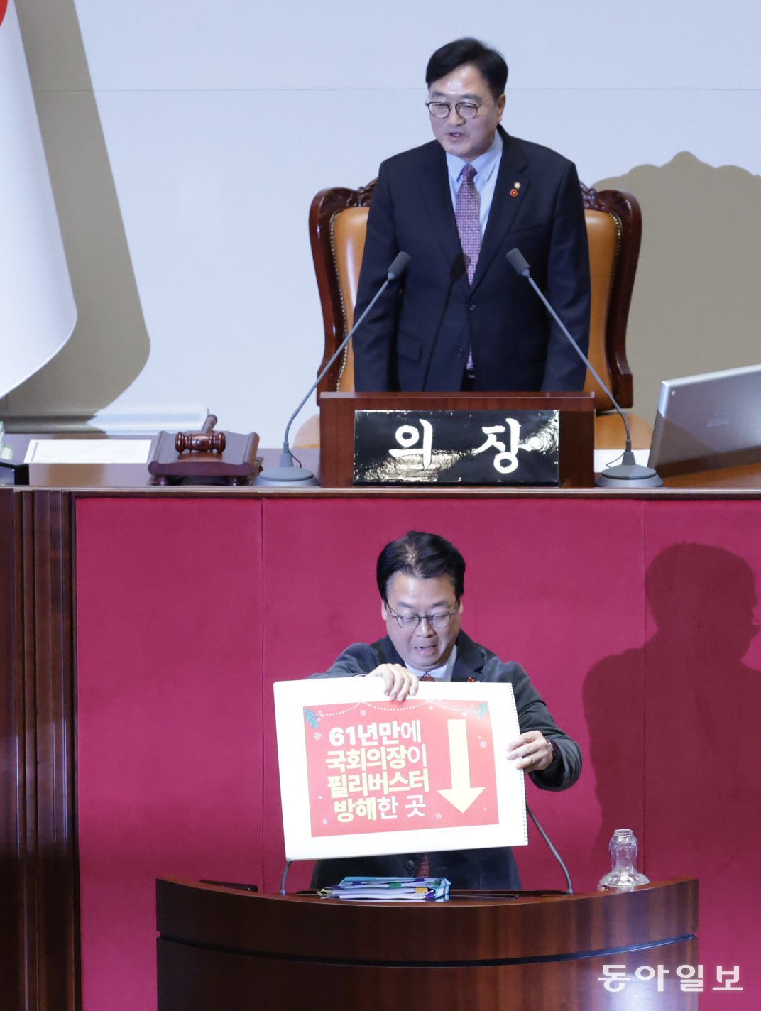 국민의힘 곽규택 의원이 11일 서울 여의도 국회에서 열린 본회의에서 ‘국회의장님 또 마이크 끄시게요’, ‘61년만에 국회의장이 필리버스터 방해한 곳’ 등이 적힌 피켓을 들고 무제한 토론을 하고 있다. 곽 의원 뒤로 우원식 국회의장이 국회 직원들과 대화하고 있다. 박형기 기자 oneshot@donga.com