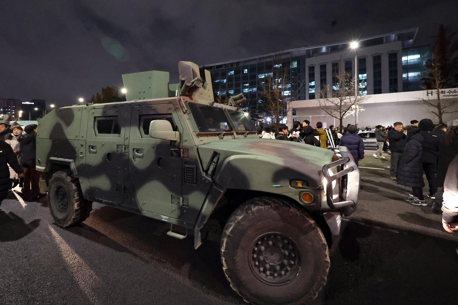 지난해 12월 4일 새벽 서울 여의도 국회 앞 계엄군 차량 뒤로 군 헬기가 경내로 비행하고 있다./뉴스1