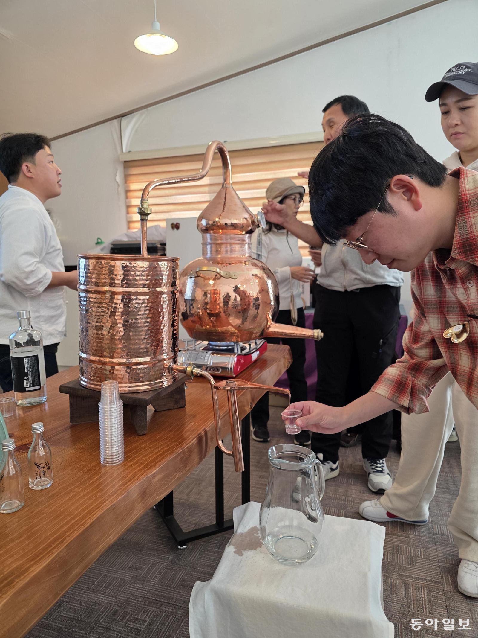 소줏고리에서 증류돼 나온 78도짜리 안동소주 원액을 맛보는 체험객.