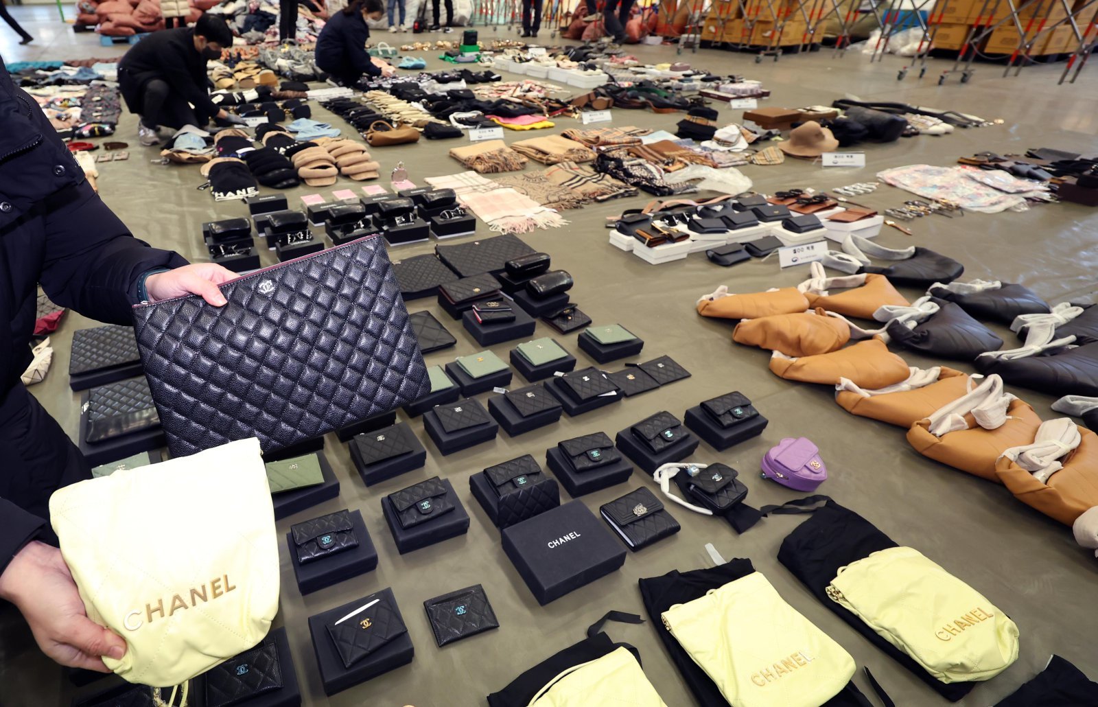 부산세관 직원들이 9일 부산 강서구 부산세관신항지정장치장에서 유통업자로부터 압수한 중국산 짝퉁 제품들을 정리하고 있다.     부산세관은 중국서 가방, 의류 등 시가 200억원 상당의 짝퉁 제품 1만여 점을 제작해 특송화물로 밀반입한 뒤 주택가 인근 원룸에 보관하며 온라인 쇼핑몰을 통해 판매한 전자상거래업체 대표 A(40대·여)씨를 관세법, 상표법, 범죄수익은닉의규제및처벌등에관한법률 위반 등의 혐의로 검찰에 불구속 송치했다고 밝혔다. 2025.01.09. [부산=뉴시스]