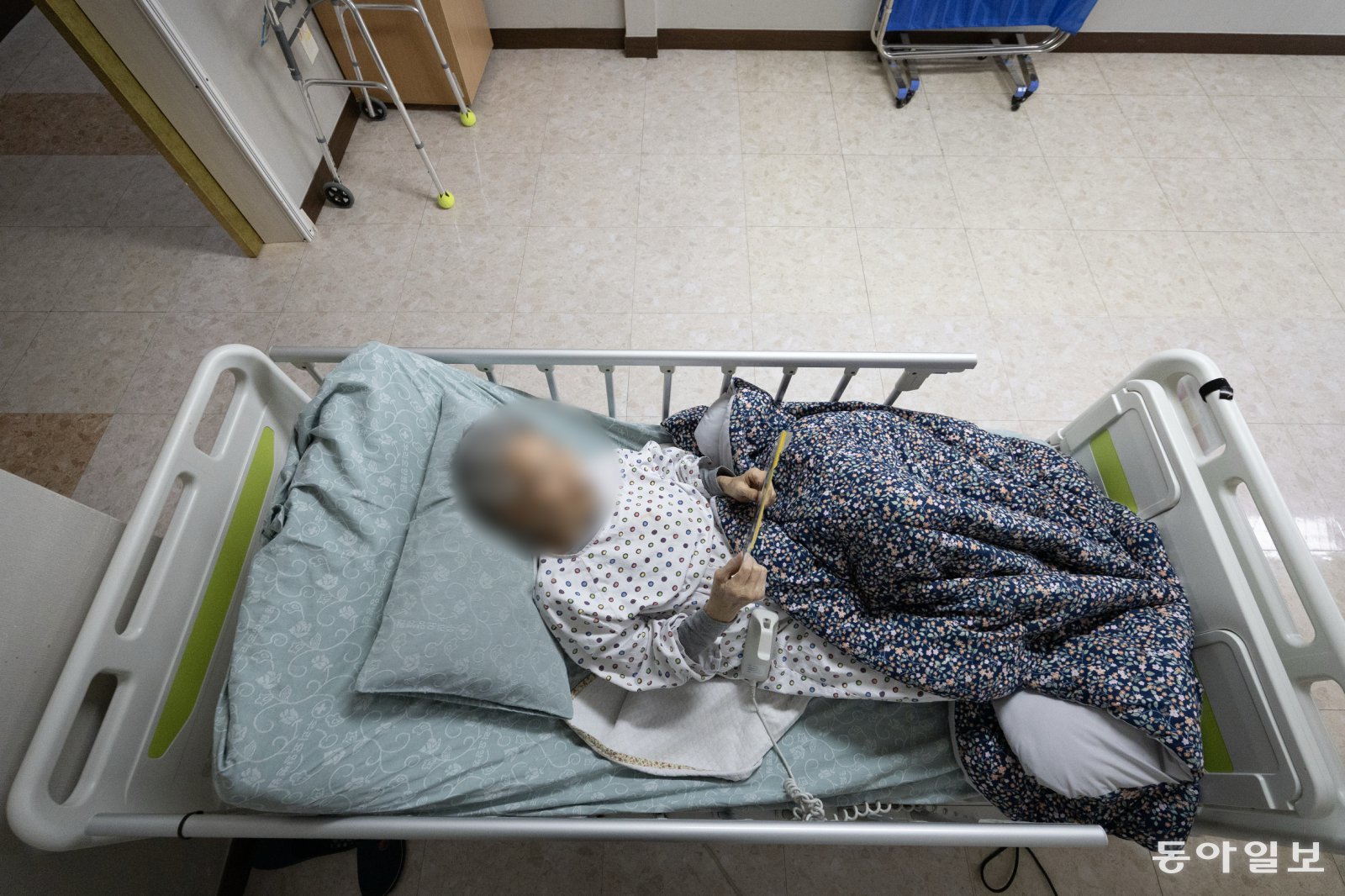 올 초 요양원에 입소한 최명자 씨가 전동침대에 누워 가족사진을 들고 바라보고 있다.