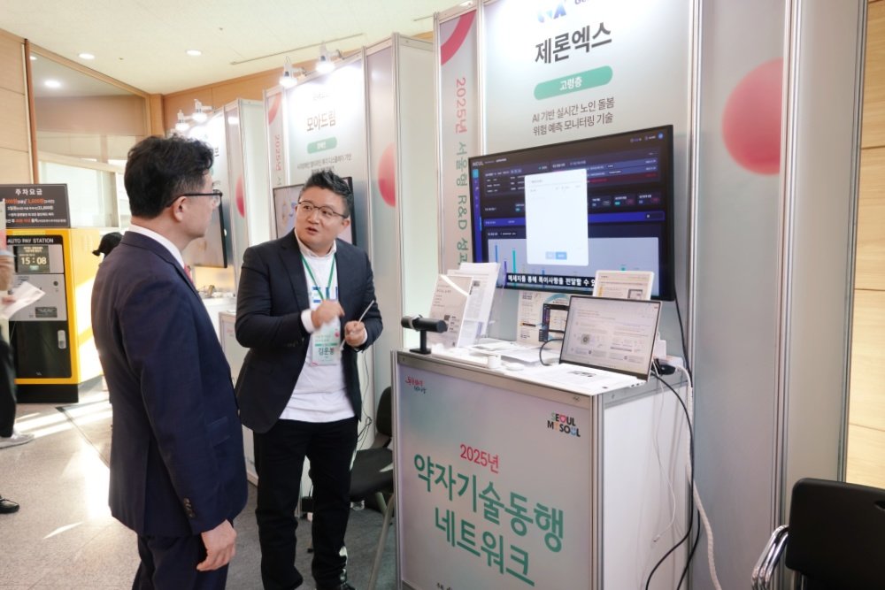 주용태 서울시 경제실장이 2025년 서울형 R&D 성과공유회의 약자기술시연회에서 제론엑스의 설명을 듣고 있는 모습 / 출처=IT동아