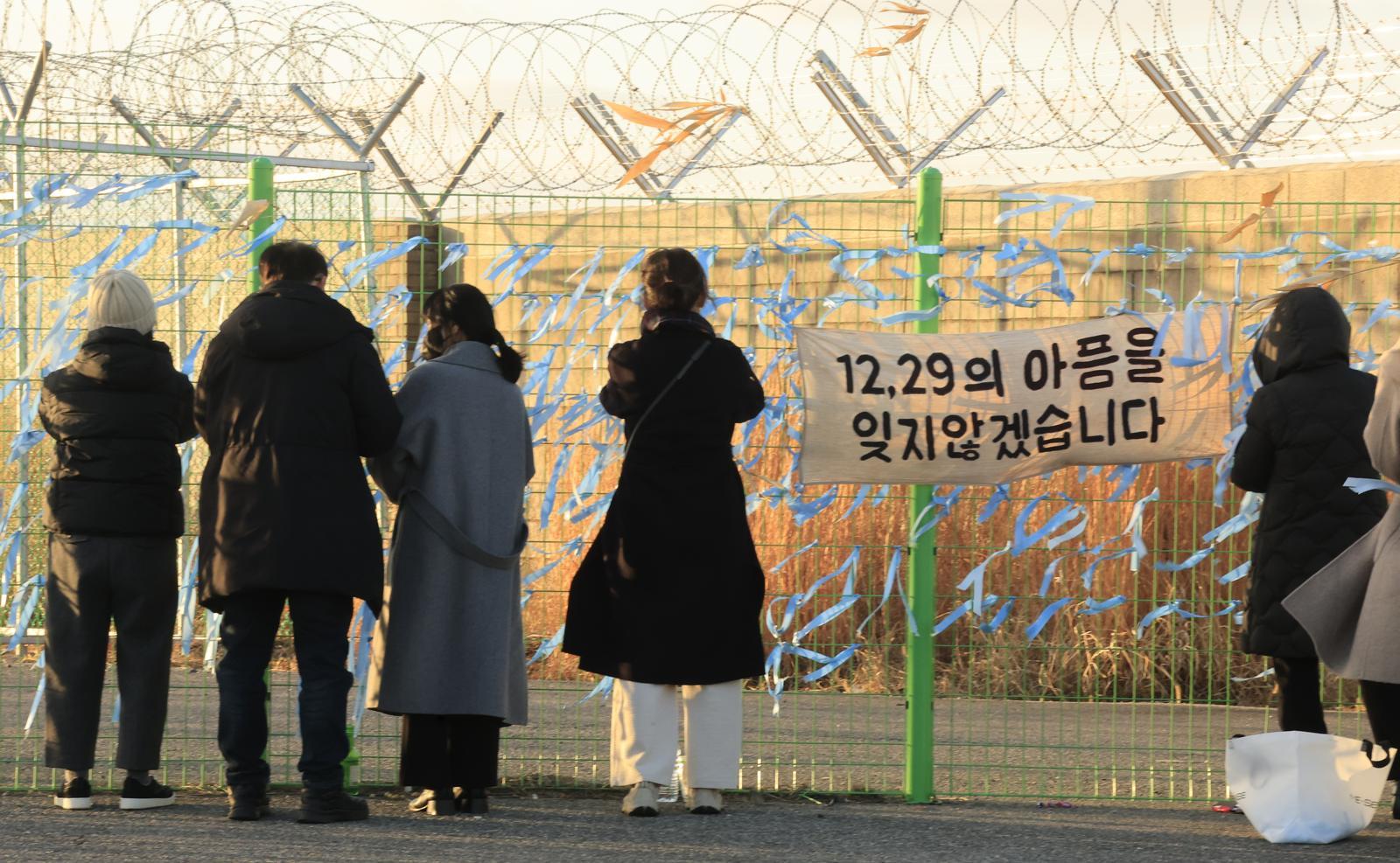 제주항공 여객기 참사 1주기를 앞둔 21일 전남 무안국제공항 사고 현장 인근 공항 철조망에서 희생자 유가족들과 추모객들이 파란린본을 매달고 있다. 무안=박영철 기자 skyblue@donga.com