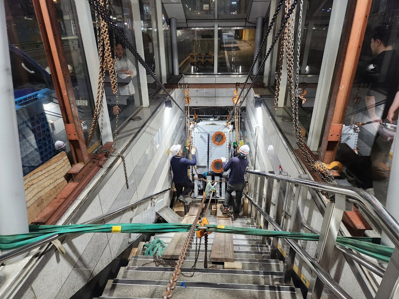 크레인을 활용해 대형 설비를 건물 외벽 개구부로 인양 및 설치하는 작업 현장.