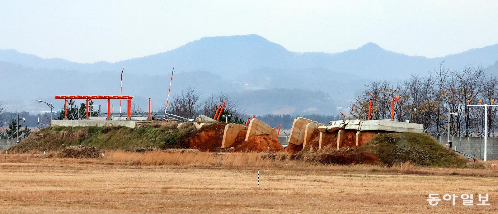 12·29 무안공항 제주항공 여객기 참사 1주년을 나흘 앞둔 25일, 전남 무안군 무안국제공항 활주로 바깥의 콘크리트 둔덕이 일부 무너져 있다. 국토교통부는 당시 피해를 키웠던 이 둔덕을 포함한 전국 7개 공항의 방위각 시설(로컬라이저)을 고치기로 했지만 이날까지 공사가 완료된 곳은 광주공항과 포항경주공항 2곳뿐이다. 무안=박영철 기자 skyblue@donga.com