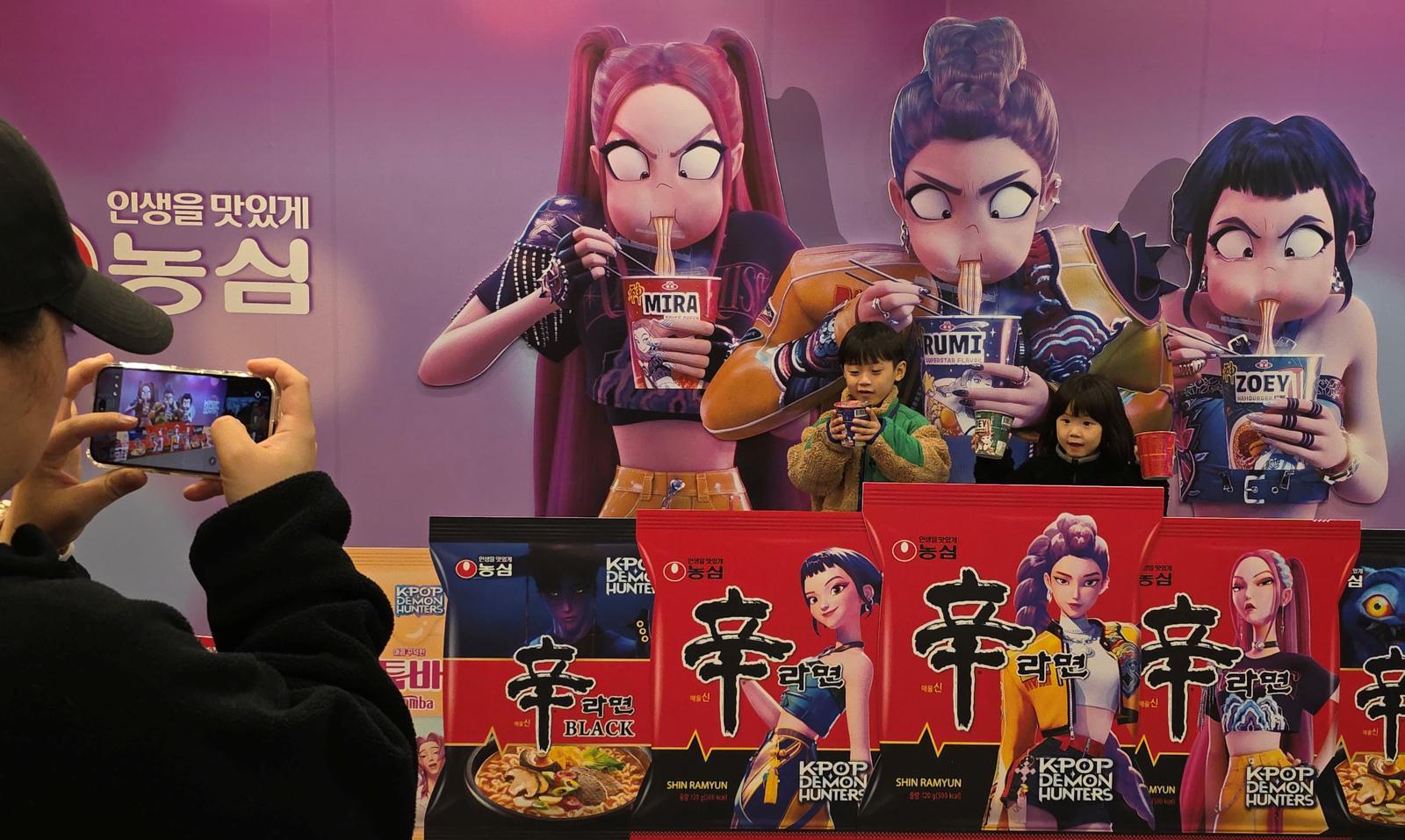 ‘2025 구미라면축제’ 행사장을 찾은 방문객들이 넷플릭스 애니메이션 영화 ‘케이팝 데몬 헌터스’ 가 라면을 먹는 모습을 배경으로 기념사진을 찍고 있다. 뉴스1