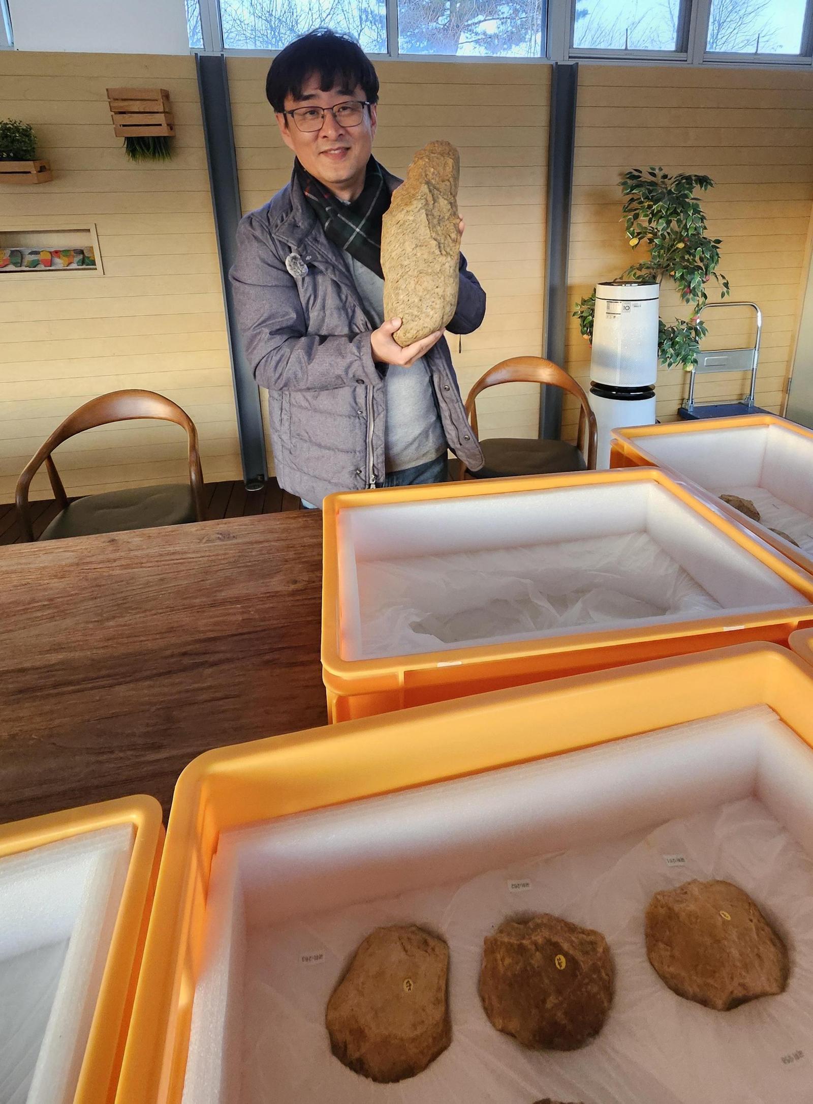 2024년 경기 연천군 전곡리에서 출토된 길이 42cm, 무게 10kg의 대형 주먹도끼를 강인욱 교수가 들어 보이고 있다. 이한용 전곡선사박물관장 제공