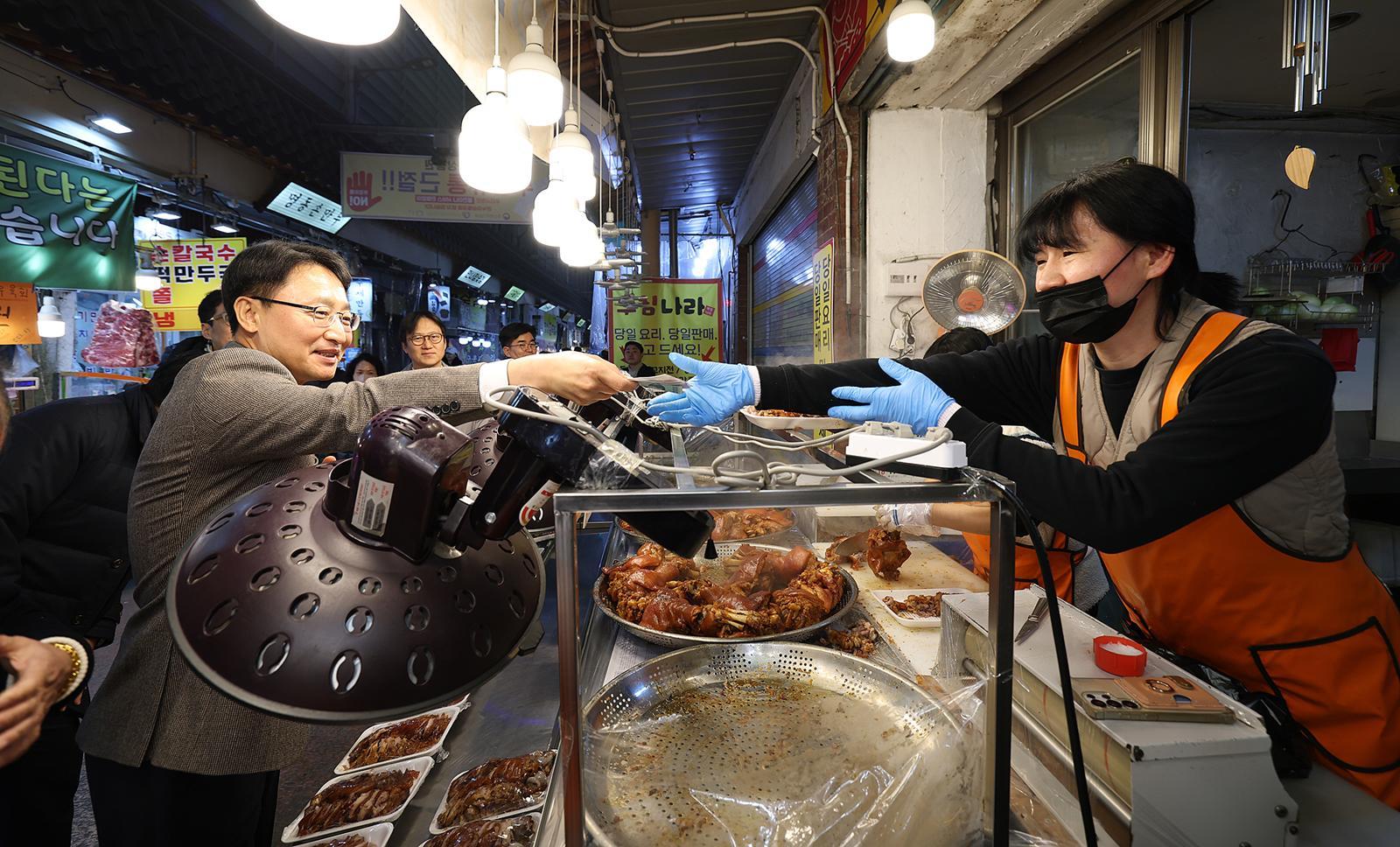 임광현 국세청장(왼쪽)이 6일 경기 수원시 못골시장에서 먹거리를 산 뒤 돈을 내고 있다.  뉴스1