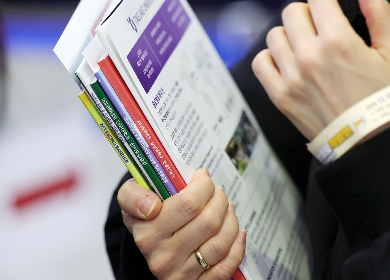 18일 서울 강남구 코엑스에서 열린 2026학년도 정시 대학입학정보박람회를 찾은 한 학부모가 각 대학별 정시모집요강 책자를 들고 있다. 2025.12.18. 서울=뉴시스