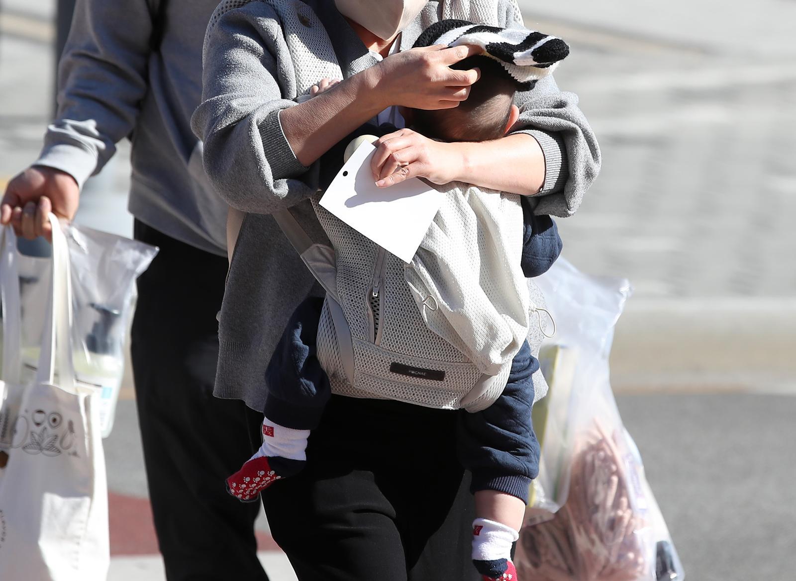 엄마가 찬바람을 가리기 위해 아기에게 털모자를 씌워주고 있다. 2025.12.4 뉴스1