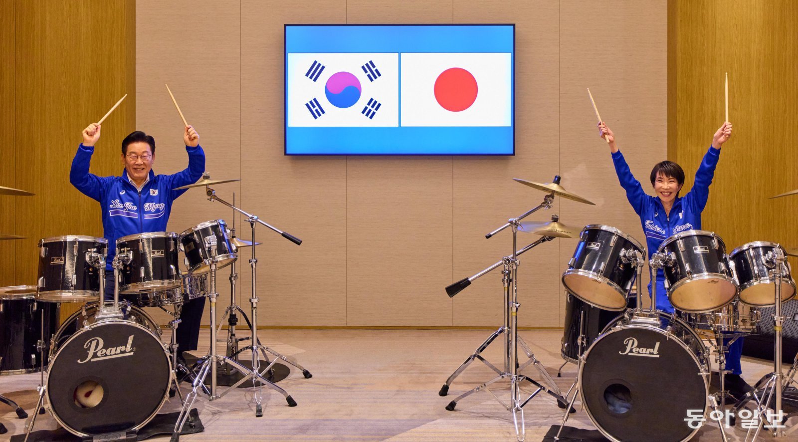 이재명 대통령과 다카이치 사나에 총리가 13일 일본 나라현의 한 호텔에서 일본 측이 마련한 푸른색 유니폼을 함께 착용하고, 일본의 대표적인 악기 브랜드인 ‘펄’ 드럼 앞에 나란히 앉아 즉석 드럼 합주를 선보이고 있다. 송은석 기자 silverstone@donga.com