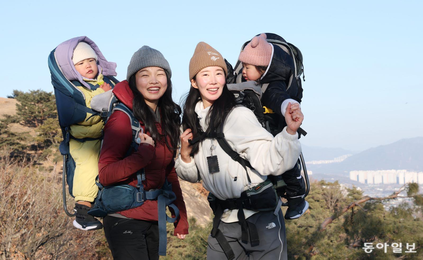 오언주 베이비하이킹클럽(베하클) 회장(왼쪽)과 김지영 씨가 각각 아들과 딸을 업고 서울 광진구 아차산 해맞이코스 1보루에 올라 활짝 웃고 있다. 신원건 기자 laputa@donga.com