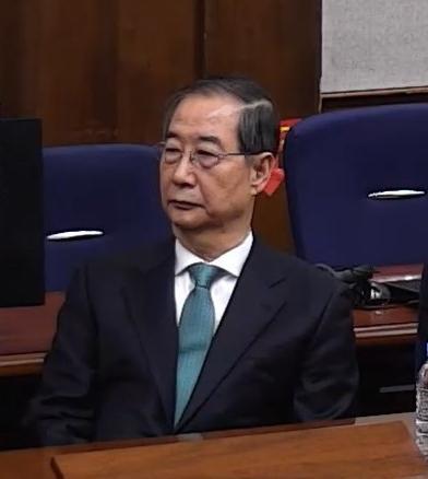 한덕수 전 국무총리가 21일 서울중앙지법에서 열린 내란 중요임무 종사 혐의 1심 선고 재판에 참석해 재판장의 발언을 듣고 있다. 서울중앙지법 재판 중계 화면 캡처