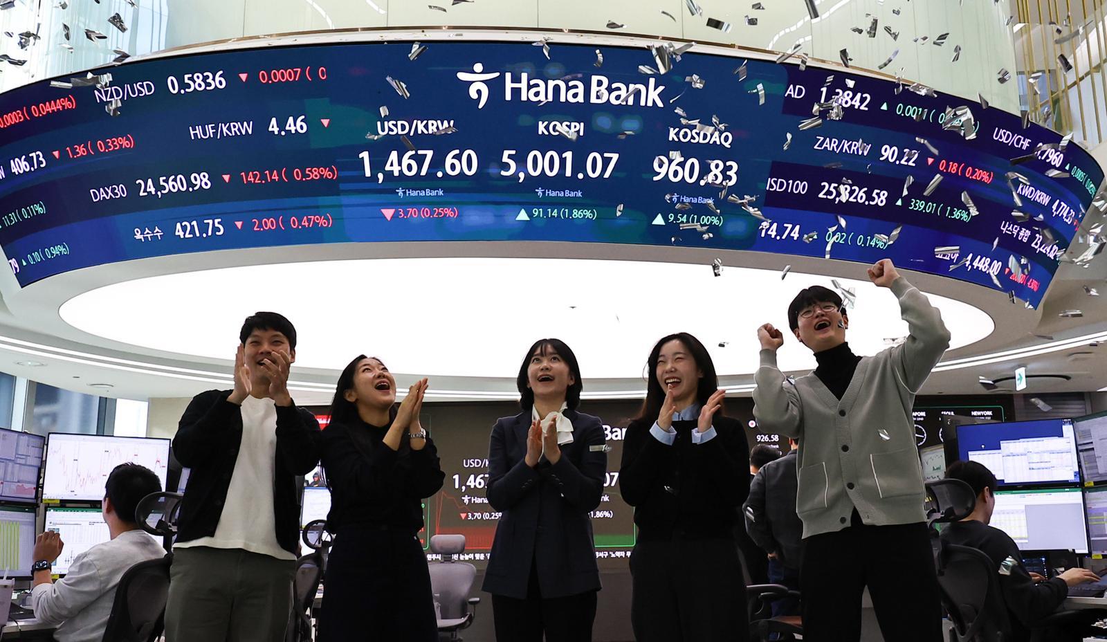 [서울=뉴시스] 최진석 기자 = 코스피가 꿈의 숫자로 여겨지던 ‘오천피’에 도달하며 코스피 5000 시대가 열린 22일 오전 서울 중구 하나은행 딜링룸에서 관계자들이 코스피 5000 돌파를 축하하고 있다. 코스피는 전 거래일(4909.93)보다 77.13포인트(1.57%) 상승한 4987.06에 개장했다.2026.01.22. myjs@newsis.com