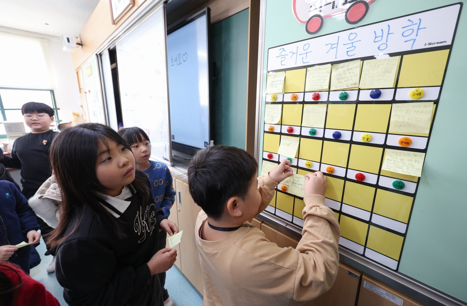 24일 서울 동대문구 안평초등학교에서 열린 겨울방학식에서 2학년 학생들이 방학에 하고 싶은 일들을 적은 포스트잇을 게시판에 붙이고 있다. 2025.12.24. [서울=뉴시스]