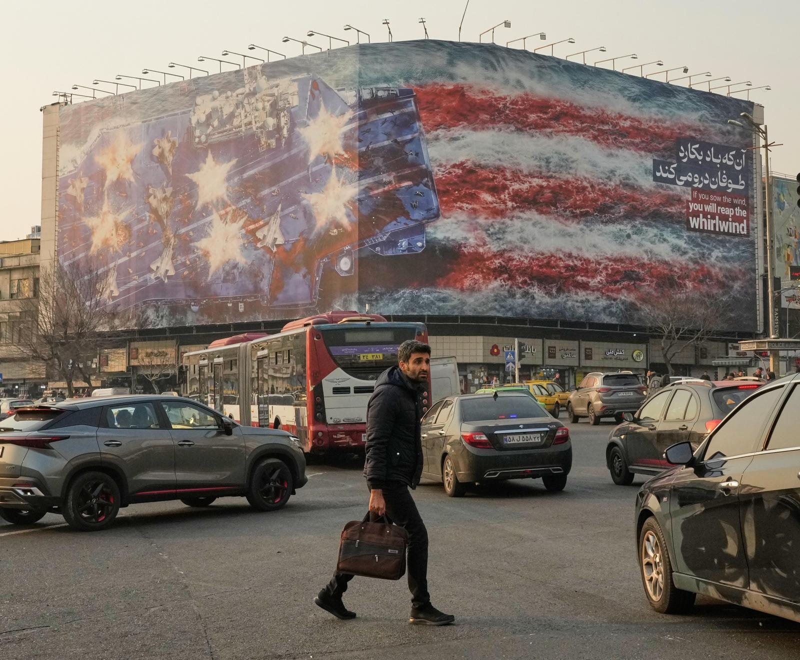 25일 이란 수도 테헤란 도심에 파괴된 미국 항공모함을 묘사한 그림이 걸려 있다. 푸른색 항공모함 갑판에서 붉은 피가 흘러내리는 모습이 멀리서 보면 ‘피에 젖은 성조기’를 연상시킨다. 테헤란=AP 뉴시스