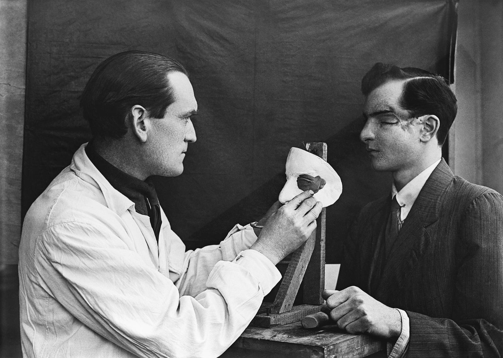 제3 런던 종합병원의 한 의사가 얼굴 손상 환자의 얼굴과 가면을 비교하면서 마무리 작업을 하고 있다. 열린책들 제공