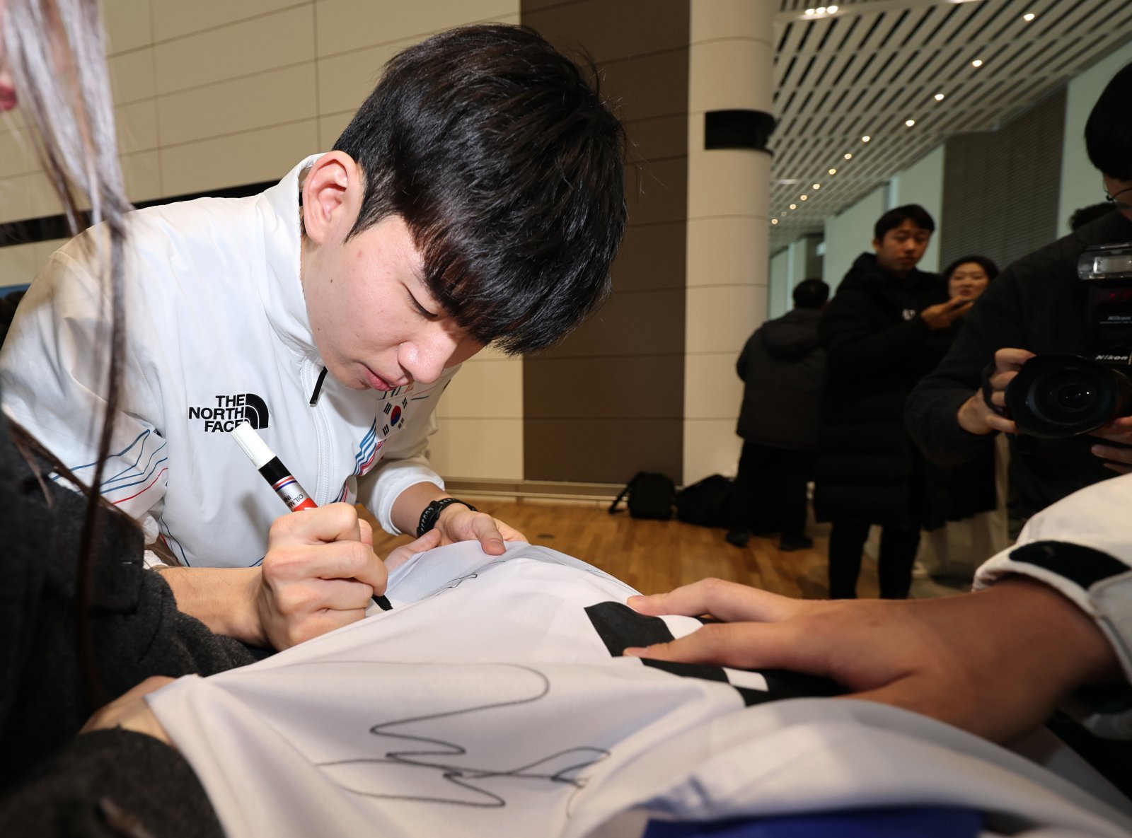 2026 밀라노·코르티나담페초 동계올림픽에 출전하는 대한민국 스피드스케이팅 대표팀의 정재원이 30일 오전 인천국제공항 제2터미널을 통해 이탈리아 밀라노로 출국 전 응원 온 팬이 가져온 태극기에 사인을 하고 있다. 2026.1.30 뉴스1