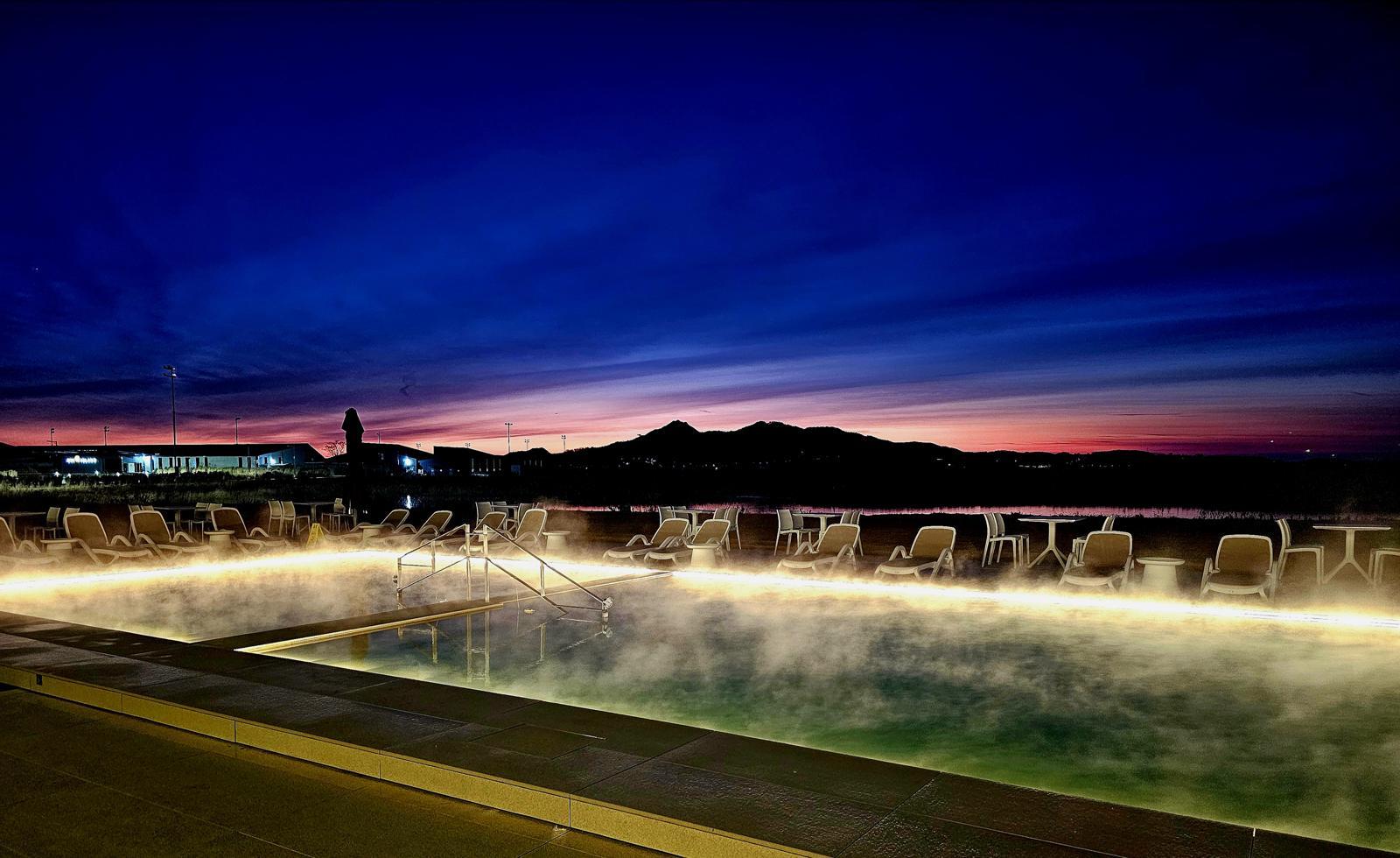 강화 석모도의 간척지 땅 너머로 펼쳐지는 새벽 일출. 유니아일랜드 더스파빌 해수온천 수영장 위로 뜨거운 수증기가 피어나고 있다.