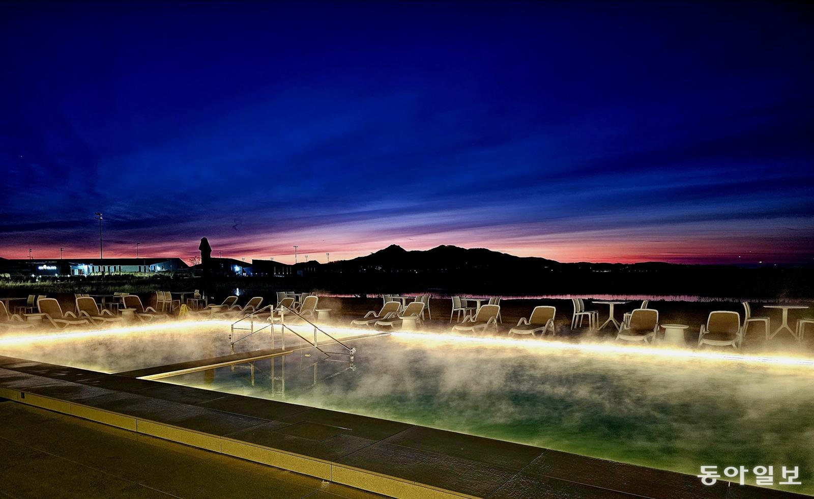 강화 석모도의 간척지 땅 너머로  펼쳐지는 새벽 일출. 유니아일랜드 더스파빌 해수온천 수영장 위로 뜨거운 수증기가 피어나고 있다.