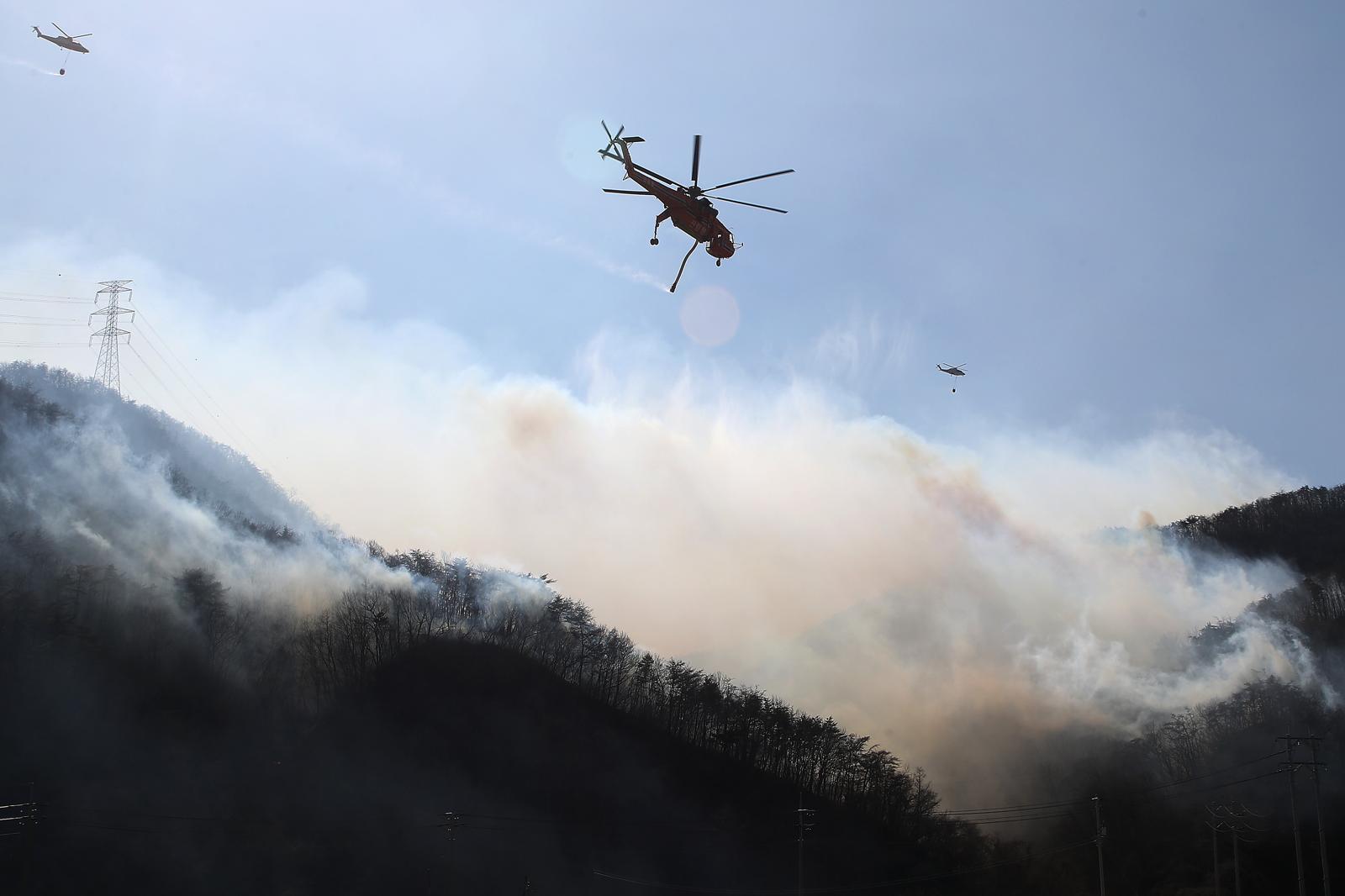 8일 오전 경북 경주시 문무대왕면 산불이 강풍을 타고 주변으로 확산하는 가운데 산불 진화에 투입된 헬기가 송전탑 주변을 날아가며 산불을 진화하고 있다. 2026.2.8. 뉴스1