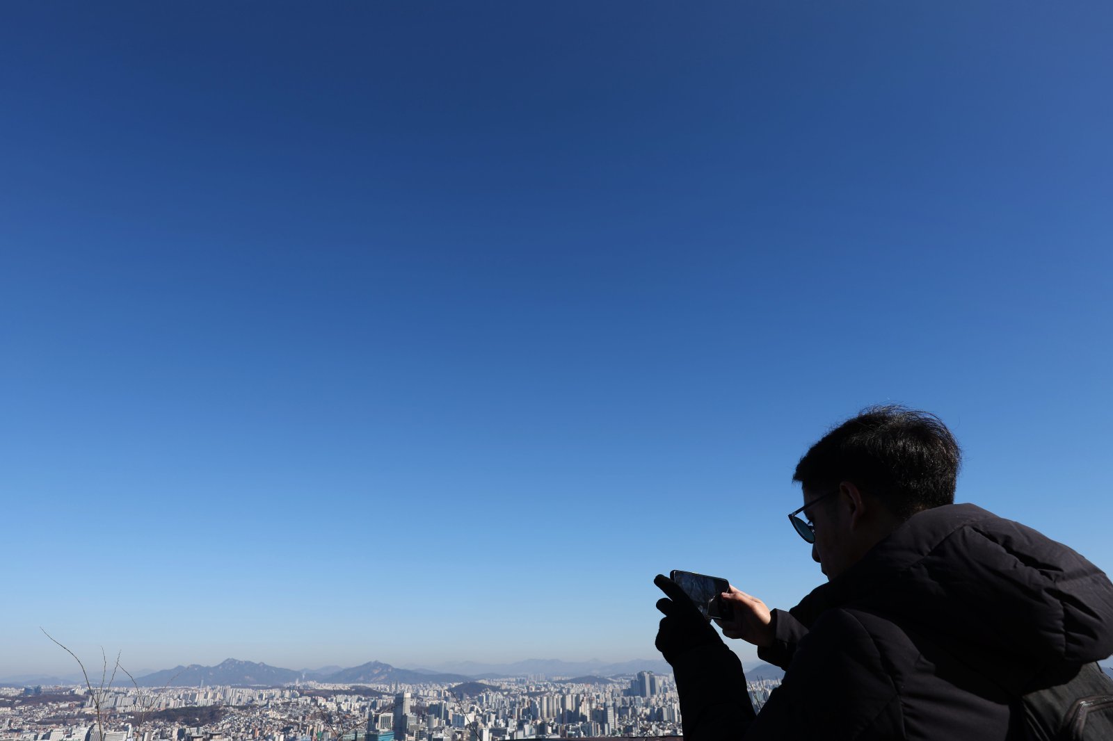 전국이 대체로 맑은 날씨를 보인 15일 서울 중구 남산을 찾은 관광객이 스마트폰으로 파란 하늘과 서울 도심을 담고 있다. 2024.01.15. 서울=뉴시스