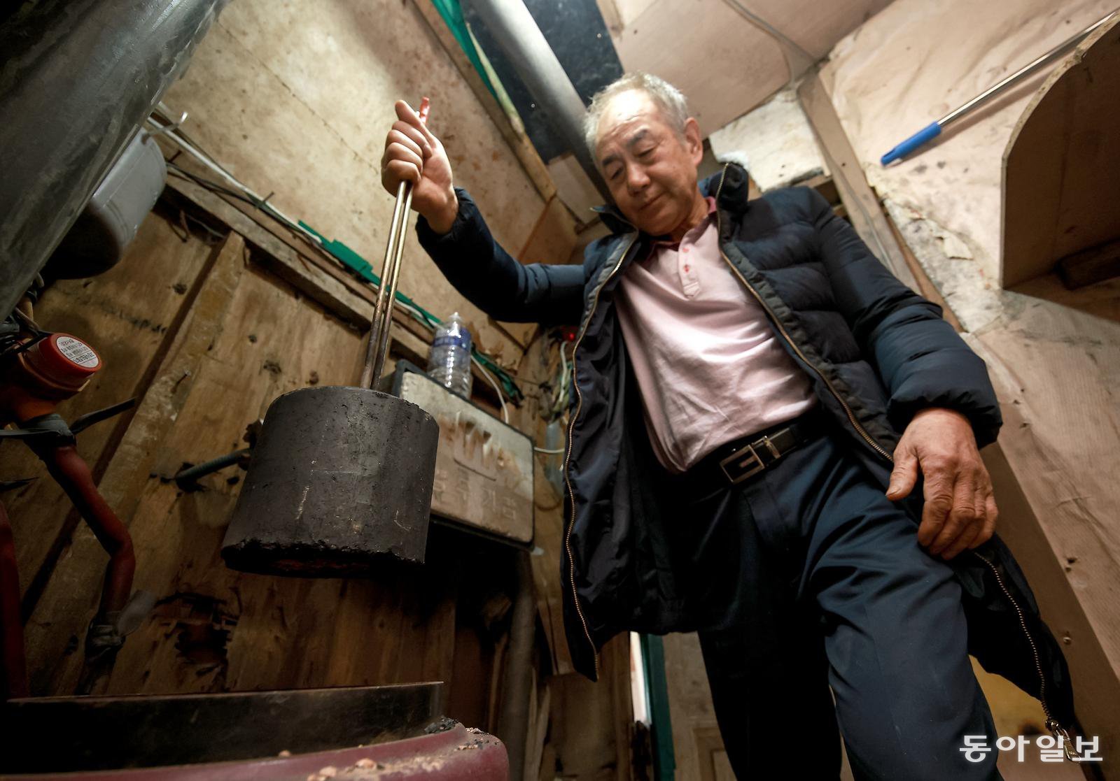 이횽규 씨가 난방을 위해 연탄을 갈고 있다. 이 씨는 남은 연탄 28장으로 한 달을 버텨야 한다. 스며드는 냉기는 두꺼운 패딩 점퍼를 껴입으며 견딘다. 송은석 기자 silverstone@donga.com