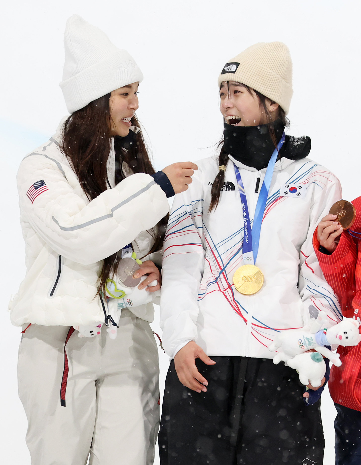 클로이 김(왼쪽)이 13일 스노보드 여자 하프파이프 경기가 끝난 후 시상대 위에서 최가온의 얼굴이 잘 나오도록 옷매무새를 가다듬어 주고 있다. 
리비뇨=뉴스1