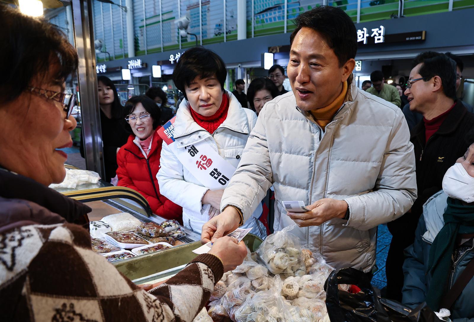 오세훈 서울시장이 설 연휴 첫날인 14일 서울 영등포전통시장을 찾아 떡을 구입하고 있다. 뉴스1