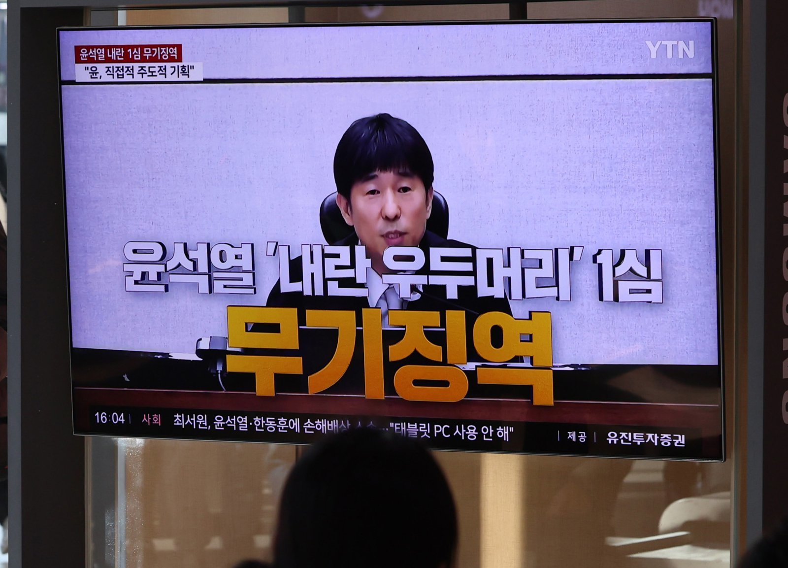 19일 오후 서울 용산구 서울역에서 시민들이 ‘내란 우두머리 혐의’ 윤석열 전 대통령의 1심 선고 공판 중계를 시청하고 있다.   윤 전 대통령은 1심에서 무기징역을 선고 받았다. 뉴시스