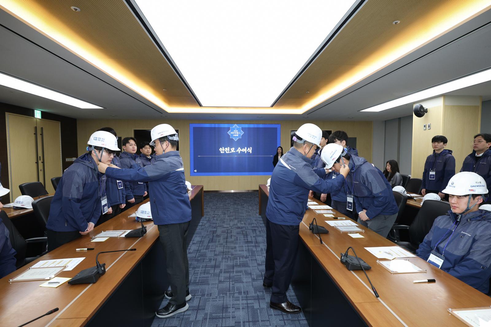 김보현 대표이사와 심상철 노동조합 위원장이 신입사원에게 안전모를 씌워주고 있다. 대우건설