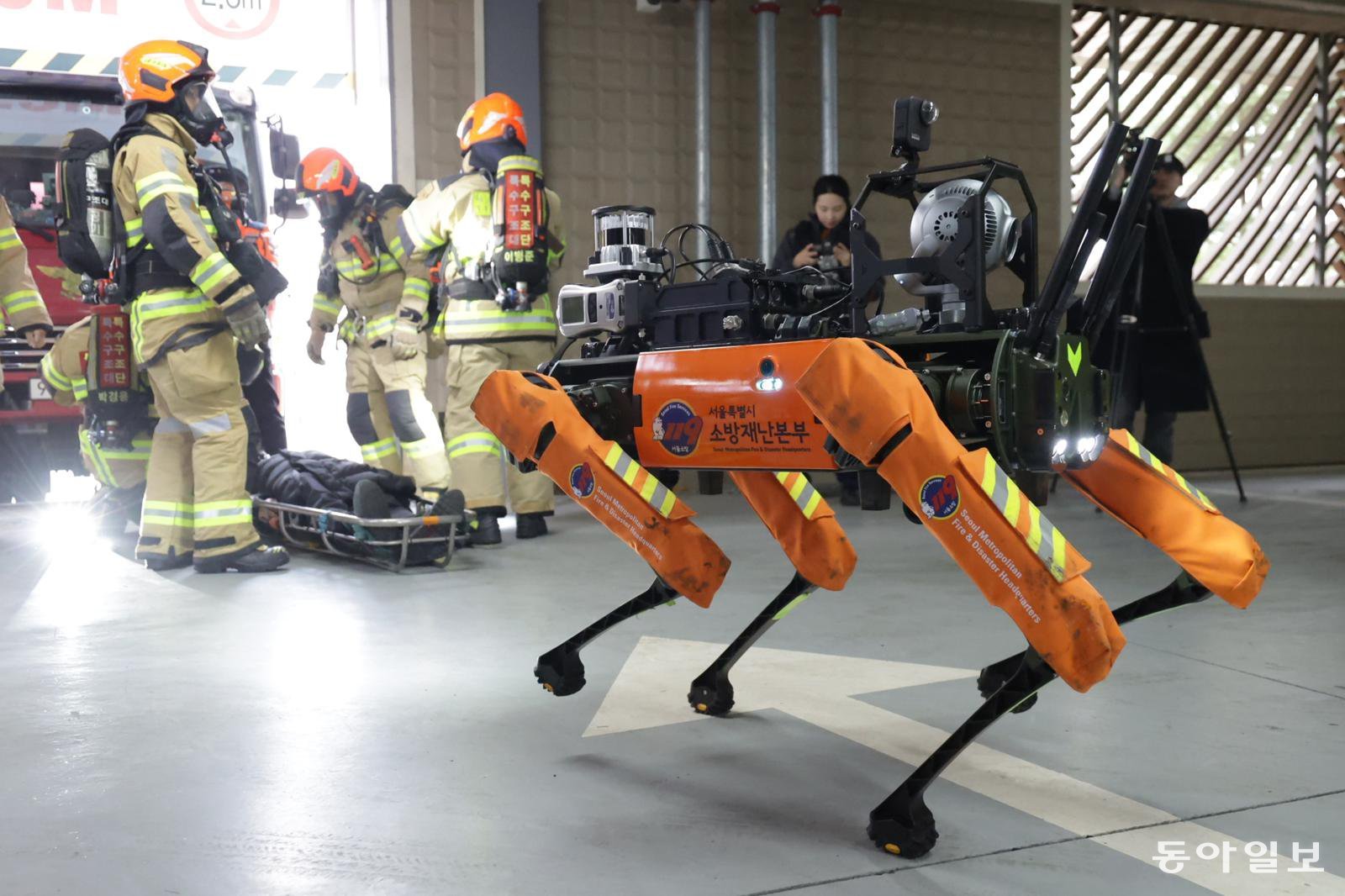 26일 소방용 4족 보행 로봇의 영상 모니터링을 보고 있던 소방대원들이 현장으로 출동해 부상자를 옮기고 있다. 박형기 기자 oneshot@donga.com