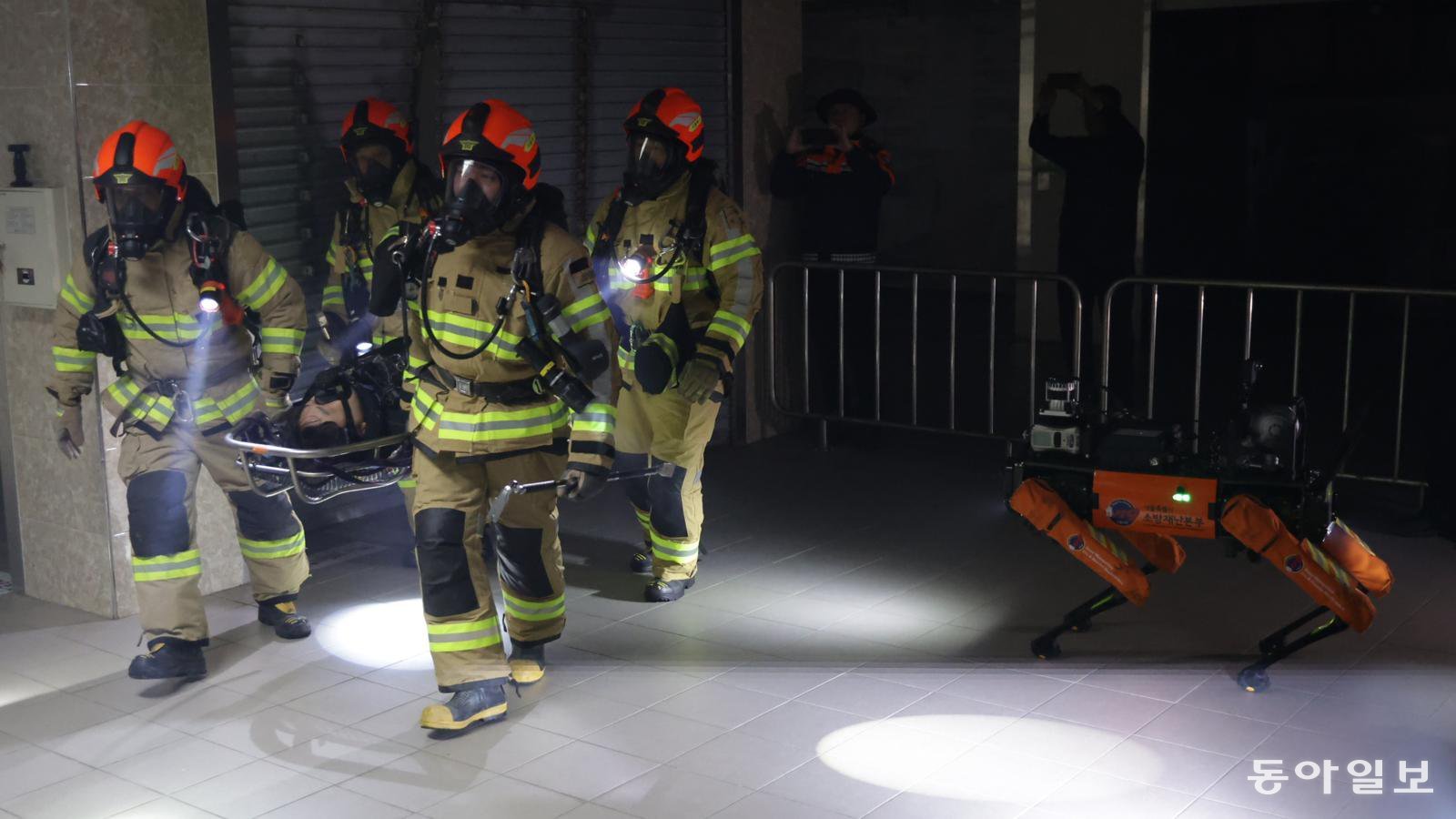 26일 소방용 4족 보행 로봇의 영상 모니터링을 보고 있던 소방대원들이 현장으로 출동해 부상자를 옮기고 있다. 박형기 기자 oneshot@donga.com