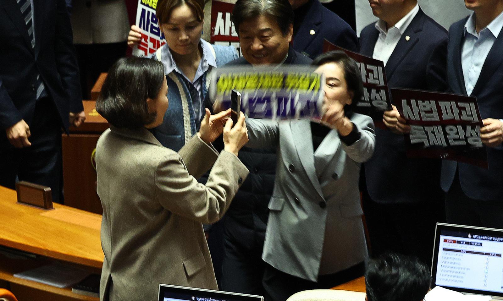 서명옥 국민의힘 의원이 27일 오후 서울 여의도 국회 본회의에서 ‘사법개혁 3법 반대’ 관련 구호가 적힌 현수막과 피켓을 들고 항의 하던 도중 이를 촬영하는 이해민 조국혁신당 의원의 핸드폰을 피켓으로 내리치려 하고 있다. 2026.02.27. 서울=뉴시스