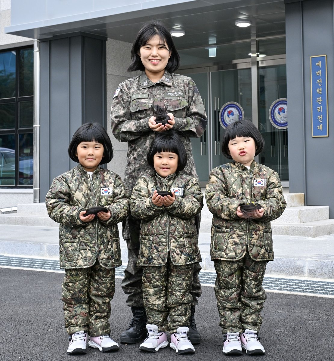이은주 해군 상사와 세쌍둥이 딸들이 지난달 26일 소아암 아동 돕기를 위해 자른 각 25cm 길이의 머리카락을 손에 들고 기념사진을 촬영하고 있다. 해군 제공