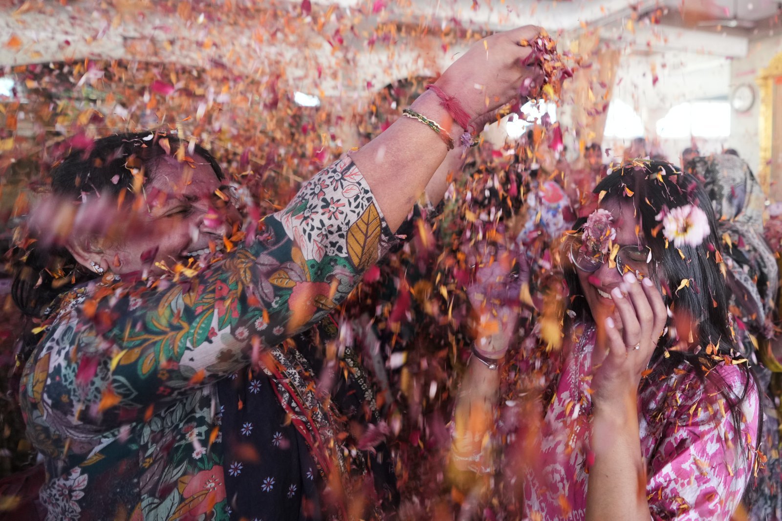 3일(현지 시간) 인도 아마다바드 자간나트 사원에서 한 여성이 힌두교 색 축제 ‘홀리’(Holi)를 맞아 신자들에게 꽃잎을 뿌리고 있다. 2026.03.03 아마다바드=AP 뉴시스