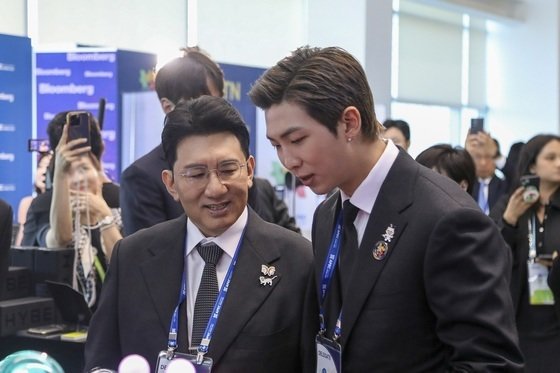 방시혁 하이브 의장(왼쪽)과 방탄소년단 RM이 지난해 개최된 ‘APEC CEO 서밋’에서 하이브 부스를 둘러보고 있다. (하이브 제공) 뉴스1