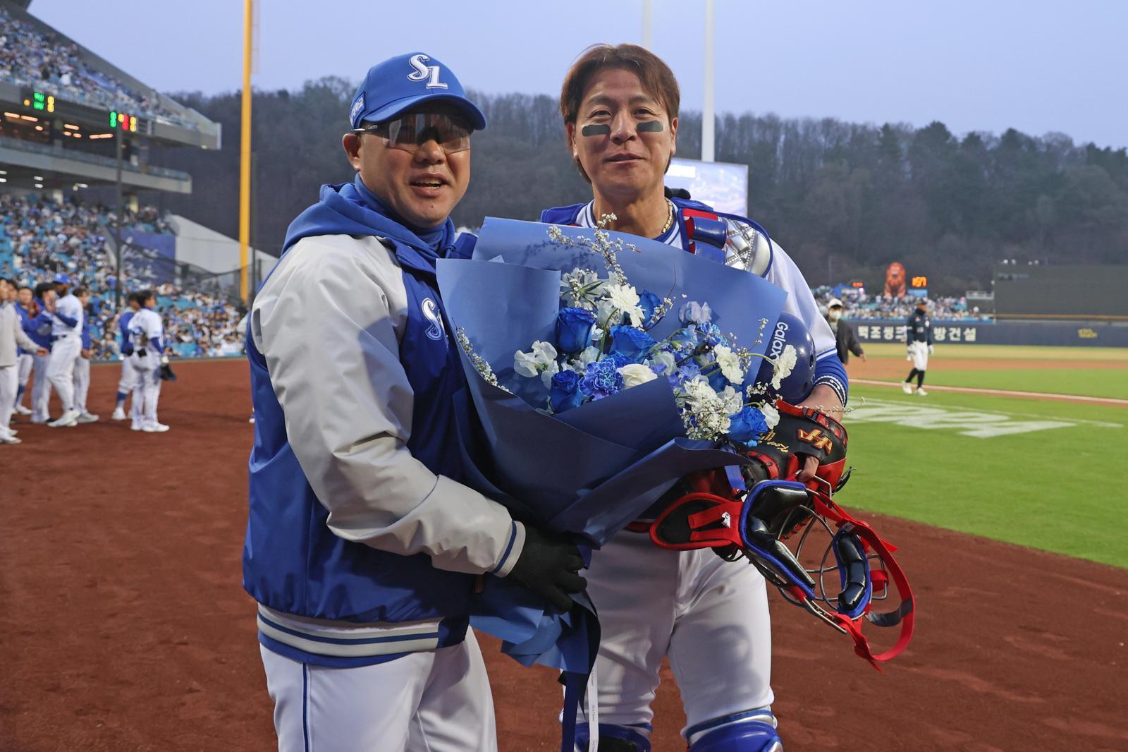 프로야구 사상 처음으로 2500경기에 출장 기록을 세운 강민호(오른쪽)가 박진만 감독에게 축하 꽃다발을 받고 있다. 삼성 제공