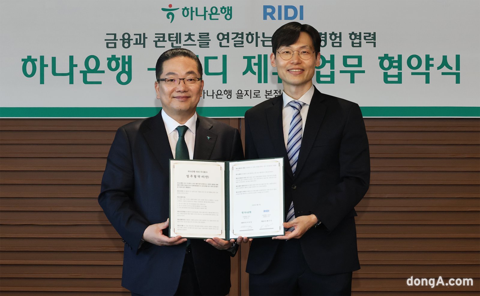 하나은행은 지난 10일 오후 서울 을지로 본점에서 국내 대표 콘텐츠 플랫폼 기업 리디(RIDI) 주식회사와 함께 금융·콘텐츠 결합을 통한 새로운 손님 경험 제공을 위해 업무협약을 체결했다고 밝혔다. 이날 협약식에 참석한 이호성 하나은행장(왼쪽)은 배기식 리디 대표이사와 함께 협약서를 들고 기념촬영을 하고 있다. 하나은행 제공