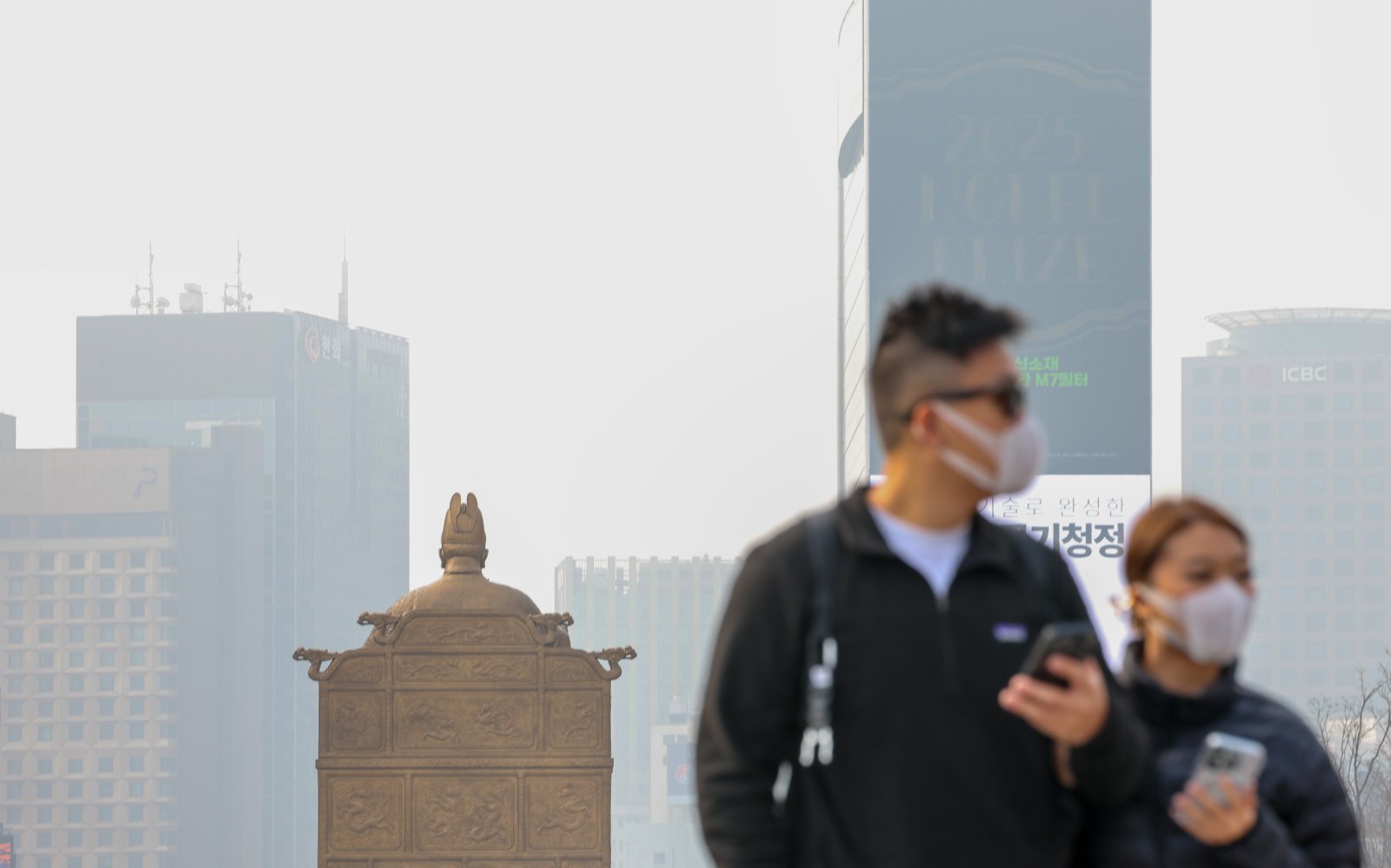 27일 오전 서울 종로구 광화문광장 세종대왕 동상 앞을 마스크를 쓴 시민이 지나가고 있다. 2026.3.27 뉴스1